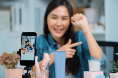 Genç, güzel Asyalı kozmetik makyaj ruju matte pastel rengini modern odadaki sosyal medyada kol testi tanıtımında en çok satanlar listesinde gösteriyor. Taktik.