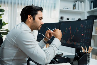 Akıllı tüccar işadamı, modern merkez ofisindeki araştırma pazarında en yüksek kârlı finansal teknolojiye yatırım yaparak bilgisayar üzerinde iki dinamik borsa yatırım ekranını analiz ediyor. Tahmin et..