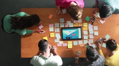 Yazılımcının web tasarımı hakkında beyin fırtınası yapması ve planlaması tablet kablo prototipine bakarken zaman aşımı. Yetenekli müteahhit takımının dijital uygulamadan bahseden hava görüşü. Sempozyum.