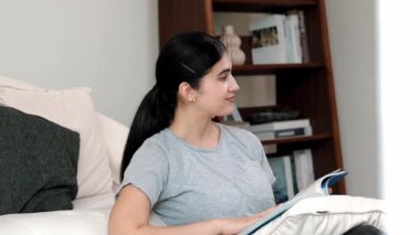 Kanepede oturan bir kadın ders kitabı okuyarak sosyal ve mesleki teknoloji bilgisini artırır ya da akıllı bir anne olmak için çocuk yetiştirir. Hayat boyu öğrenme konsepti. Uyumsuzluk.