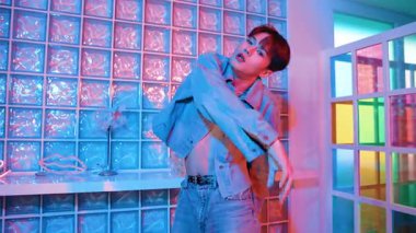 Çekici Asyalı sanatçı parlak neon ışıkta adım atıyor. Kameraya özgüvenle bakarken serbest stil müzikle dans eden yakışıklı break dans. Profesyonel hippi rahatla. Mutluluk.