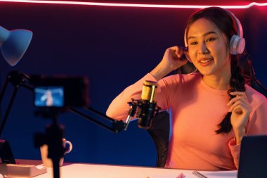 Yaratıcı yayın kanalı sosyal medyada pozitif podcasttaki dinleyicilerle birlikte müziği dinliyor, pastel renkli kulaklıklar takıyor, neon stüdyodaki kameraların mikrofon kayıtlarını kullanıyor. Taktik.