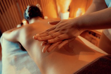 Masör elleri kadının sırtına aroma yağı döküyor. Masözler lüks otellerdeki kaplıca salonundaki müşteriler için yağ masajı prosedürü hazırlıyorlar. Aroma yağı vücut masajı konsepti. Sessiz.