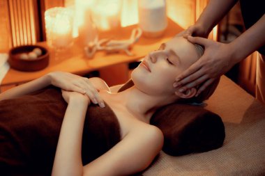 Beyaz kadın stres önleyici kafa masajı yapmaktan ve lüks otel veya otelde sıcak mum ışığında yüz güzelliği eğlencesi yapmaktan zevk alıyor. Sessiz.