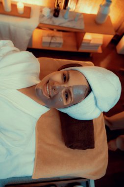 Kaplıca salonunun sakin atmosferi, üst düzey kadın müşteri sıcak mum ışığında kömür kömürü yüz kremi masajıyla kendini yenilemeye çalışıyor. Yüz bakımı ve güzellik konsepti. Sessiz.