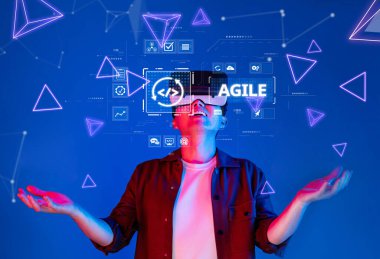 Genç bir adam, yeniliği sembolize eden canlı holografik elementler ve dijital arayüzlerle çevrili sanal gerçeklik kulaklığı aracılığıyla çevik teknolojinin heyecanını yaşıyor. XDMCP