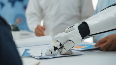 Gelecekçi bir robotik el, bir iş toplantısı sırasında masadaki belgelerle etkileşime girer ve teknolojinin profesyonel ortamlara entegrasyonunu gösterir. Noogenesis