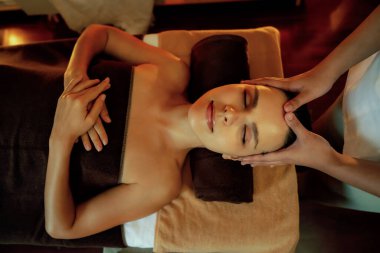 Beyaz kadın stres önleyici kafa masajı yapmaktan ve lüks otel veya otelde sıcak mum ışığında yüz güzelliği eğlencesi yapmaktan zevk alıyor. Sessiz.