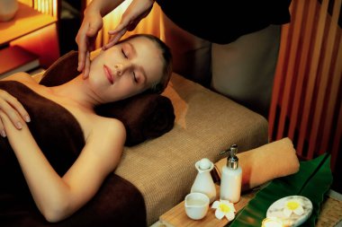 Beyaz kadın stres önleyici kafa masajı yapmaktan ve lüks otel veya otelde sıcak mum ışığında yüz güzelliği eğlencesi yapmaktan zevk alıyor. Sessiz.