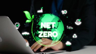 Çevresi dijital grafiklerle çevrili, çevresi eko-dost girişimler ve küresel sürdürülebilirliği vurgulayan net sıfır emisyonlar elde etme konulu bir tartışmayla ilgilenen bir iş adamı. Dörtgen