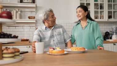 Büyükannem kahvaltısını sunarken, gülümseyen büyükbaba masada oturuyor. Yaşlı çift konuşuyor ve birlikte vakit geçiriyorlar ya da birlikte destek oluyorlar. Sağlıklı ilişki kavramı. Myrmidon.
