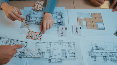 Tasarımcıların elleri aktif olarak renk örnekleri seçmek ve bir iç tasarım projesi için masadaki mimari planları analiz etmek için bir işbirliği oturumuna katılıyorlar. SACTR