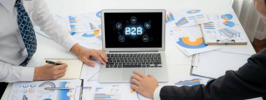 İş adamı B2B peyzajında geziniyor, iş-iş bağlantılarını geliştirmek için kullanım teknolojisi kullanıyor. B2B etkileşimini yeniden şekillendiren keşifler, iş-iş stratejilerinde yenilikleri yönlendiren araçlar. canlı