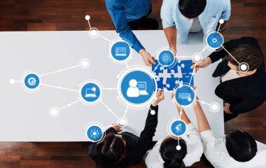 Modern bir iş ortamında takım çalışmasını ve dijital bağlantıları sembolize eden, çeşitli profesyonellerin bir bulmaca parçası üzerinde işbirliği yaptığı dinamik bir sahne. Dostluk