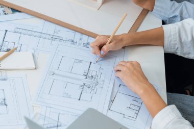 Asyalı kooperatif iş arkadaşı ev modelini ev modeliyle ve bina planıyla birlikte masaya koyarken, profesyonel güzel mimarın el yapımı taslaklarının en üst görüntüsü. Tertemiz..