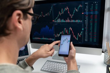 Akıllı borsa yatırımcıları ekranda akıllı telefon ile piyasa borsasını işaret ederek dizüstü bilgisayarın yanı sıra en yüksek dinamik yatırım oranını göstererek, modern işyerindeki veri planlamasına odaklanıyorlar. Bireysel.