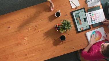 Renk paletinden renk seçmek için birlikte çalışan iş adamlarının üst düzey hava görüşü. İşadamı logo grafiğine bakarken pazarlama ekibine tablet kullanarak yönetici fikri sundu. Sempozyum.