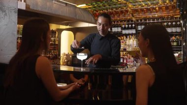 Asyalı akıllı barmen votka bardağını karıştırdı. Çiçek, lüks tezgah barında özel içki yapan güzel müşteriye servis edildi. Ferahlatıcı alkol gece hayatı lüksü. Vinosity.