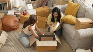 Lezbiyen aşıklar taşınma gününde karton kutudan nesneleri alıyorlar. Taşınırken paketleri açmak ve kutudan mobilya toplamak için birlikte çalışan bir çift oda arkadaşı. Yer değiştirme konsepti. Myrmidon.