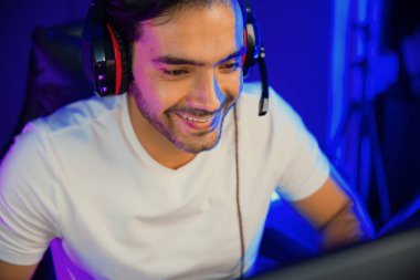 Dijital neon ışıklı stüdyo odasındaki sosyal medya uygulamasında diğer canlı yayınlarla iletişim kurmak için kulaklık ve mikrofon kullanan takım üyeleriyle konuşan akıllı oyun flaması portresi. Tahmin et..