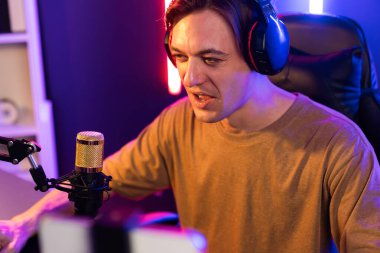 Oyun kanalı, online oyun oynayan akıllı flamalı oyun sunucusu, kulaklık takan, neon ışıklandırma odasındaki takım oyuncusuyla akıllı telefondan canlı yayında konuşan izleyiciler. Bireysel.