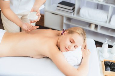 Masör elleri kadının sırtına aroma yağı döküyor. Masözler lüks otellerdeki kaplıca salonundaki müşteriler için yağ masajı prosedürü hazırlıyorlar. Aroma yağı vücut masajı konsepti. Sessiz.