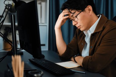 Stresli yüzü olan akıllı işadamı, gece geç saatlerde ofiste iş planı raporu hazırlamak için bilgisayar üzerinde çalışıyor ve yeni bir şirket kurma projesi için araç pazarı planlaması üzerinde çalışıyor. İnfobahn.