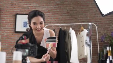 Kadın nüfuzlu kişi canlı yayın yapan video görüntülerini sosyal medya ya da blog üzerinden gözden geçiriyor. Kozmetik stüdyosu ışıklandırmalı mutlu genç kız çevrimiçi pazarlama oturumu yayını için..