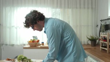 Mutlu baba yemek pişirirken müziğe geçiyor ve modern mutfakta öğle yemeği hazırlıyor. Aktif baba, sebze ve mutfak gereçleri ile çevrili sağlıklı yemek ya da salata yaparken şarkıyla dans ediyor. Pedagoji.