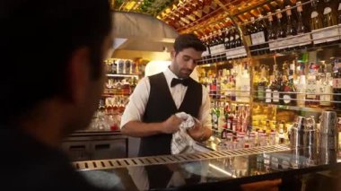 Zeki, gülümseyen barmen lüks bir barda buzlu içecekler hazırlarken aynı zamanda canlı, aydınlık atmosfer barında ve restoranda VIP müşterilerle canlı sohbetler yapıyor. Vinosity.