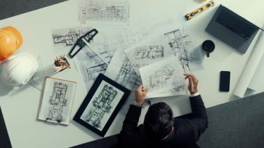 Tablet, dizüstü bilgisayar, güvenlik kaskı ve ekipmanlarla toplantı masasında otururken ev tasarımı için malzeme seçen yetenekli mühendis görüşü. Akıllı mimar proje planına bakıyor. Hizalama.