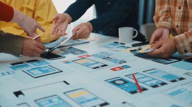 Canlı bir toplantı sahnesi, yaratıcı bir oturum sırasında renkli kablolar ve prototiplerle mobil uygulama tasarımlarını tartışan işbirlikçi bir ekibi gözler önüne seriyor. SACTR