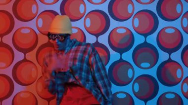 Profesyonel break dansçı, parti sahnesinde balon arka planlı gözlük takıyor. Havalı giyinen yetenekli bir sanatçı enerjik hareketler ve ayak sesleri göstererek müziğe yöneliyor. Mutluluk.