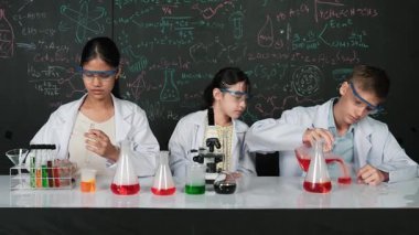 Mesleki çeşitlilik gösteren öğrenci, STEM fen dersinde, kimyasal teoriyle karatahta deneyimi yaşıyor. Genç bir delikanlı biyo-kimyasal çözeltiyi mikroskop ile masada karıştırıyor. Öğretim