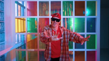 Serbest stil tişört giyerken sokak müziği çalan mutlu hipster. Gece kulübünde neon ışıkla dururken çekici break dansçı dans ve hareketli hareketler yapıyor. Mutluluk.