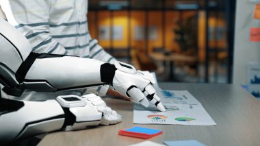 Gelecekçi bir robot, modern bir ofiste, renkli grafik ve çizelgelerin yer aldığı, ileri teknoloji ve takım çalışmalarını sembolize eden belgeleri analiz eden bir insanla işbirliği yapıyor.