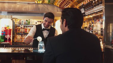 Akıllı barmen, lüks bir tezgahta arkadaşını beklerken limonlu cin kokteyli ikram ediyor. Barmen, canlı gece hayatı parti atmosferinde mükemmel hizmet veriyor. Vinosity.