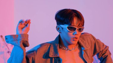 Asyalı sokak dansçısının neon ışıkla pop müziğe geçişine yakın çekim yaparken çeşitli arkadaşlar oturuyor ve performansı destekliyor. Profesyonel sanatçı stüdyoda dans figürleri yapıyor. Mutluluk.
