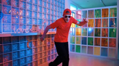 Komik break dansçı kameraya bakarken hiphop 'a doğru serbest adım atıyor. Çılgın mutlu hipster dans edip sokak dansı yaparken Led ışığında günlük kıyafet ve güneş gözlüğü takıyor. Mutluluk.