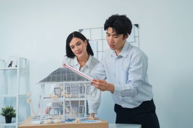 Kooperatif mühendis ekibinin portresi ev modelini ölçmek için cetvel ve mimari ekipmanlar kullanarak birlikte çalışıyor. Yaratıcı iş tasarımı ve takım çalışması konsepti. Tertemiz...