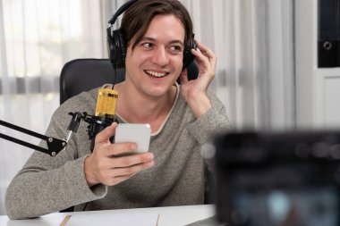 Akıllı yayıncının sunucu kanalı canlı sosyal medya yayını ile akıllı telefon kullanarak dinleyiciyle sohbet ediyor, kulaklık takarak modern ev stüdyosunda video kaydediyor. Bireysel.