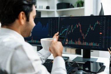 Elinde telefon dinamiğine odaklanan kahve fincanı tutan borsa yatırım ekranı veri analizini karşılaştırarak iç işlerinde yüksek kârlı finans teknolojisi pazarına yatırım yapıyor. Tahmin et..