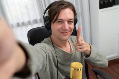 Sunucu kanalı, elinde selfie portresi ile gülümseyen akıllı yayıncı canlı sosyal medyada dinleyicilerle kamera akıllı telefonuna bakıyor, modern ev stüdyosundaki etkili yayıncı. Bireysel.