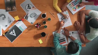 Renk paletinden renk seçmek için birlikte çalışan iş adamlarının en üst görüşü. Proje yöneticisi, logo grafiklerine bakarken pazarlama ekibine tablet kullanarak fikir sunuyor. Sempozyum.