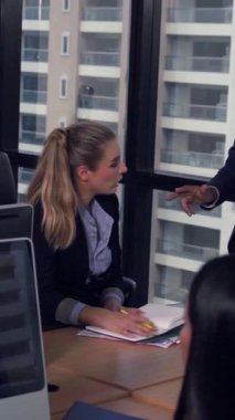 Kıdemli lider takım üyelerine tavsiye konuşması yapıyor. Modern ofisteki masada yaratıcı iş adamları buluşuyor. Çok kültürlü iş ekibi..