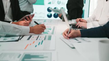 Bir iş toplantısı sırasında çeşitli profesyonellerden oluşan bir ekip, dizüstü bilgisayar ve çizelgelerde gösterilen verileri analiz ederek stratejik kararların iç yüzünü ortaya çıkarıyor. SACTR