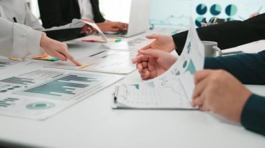 Ekip üyelerinin mali verileri analiz edip raporlarda işbirliği yaptıkları dinamik bir iş toplantısı. Dijital cihazlar tartışmayı ve sezgileri geliştirmek için kullanılır. SACTR