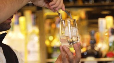 Yakın plan akıllı barmen, buzlu soda ya da tonikle bardakları dolduruyor ve ilk izlenimi çekici kostümlü profesyonellik olan içecek reyonunda müşteriye ikram ediyor. Vinosity.