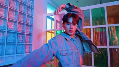 Çekici Asyalı sanatçı parlak neon ışıkta adım atıyor. Kameraya özgüvenle bakarken serbest stil müzikle dans eden yakışıklı break dans. Profesyonel hippi rahatla. Mutluluk.