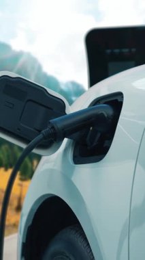 Elektro jeneratör sürücüsüyle enerji sürdürülebilir araba gücü, şarj istasyonunda şarj edilen batarya, ilerici seyahat konsepti için dağ zeminine sahip. Temiz ortamın sembolü olarak doğadaki EV otomobil.